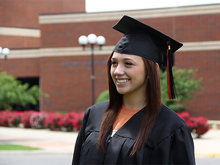 student wearing cap and gown in front of the brown center