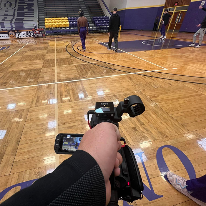 student holding camera in basketball gym