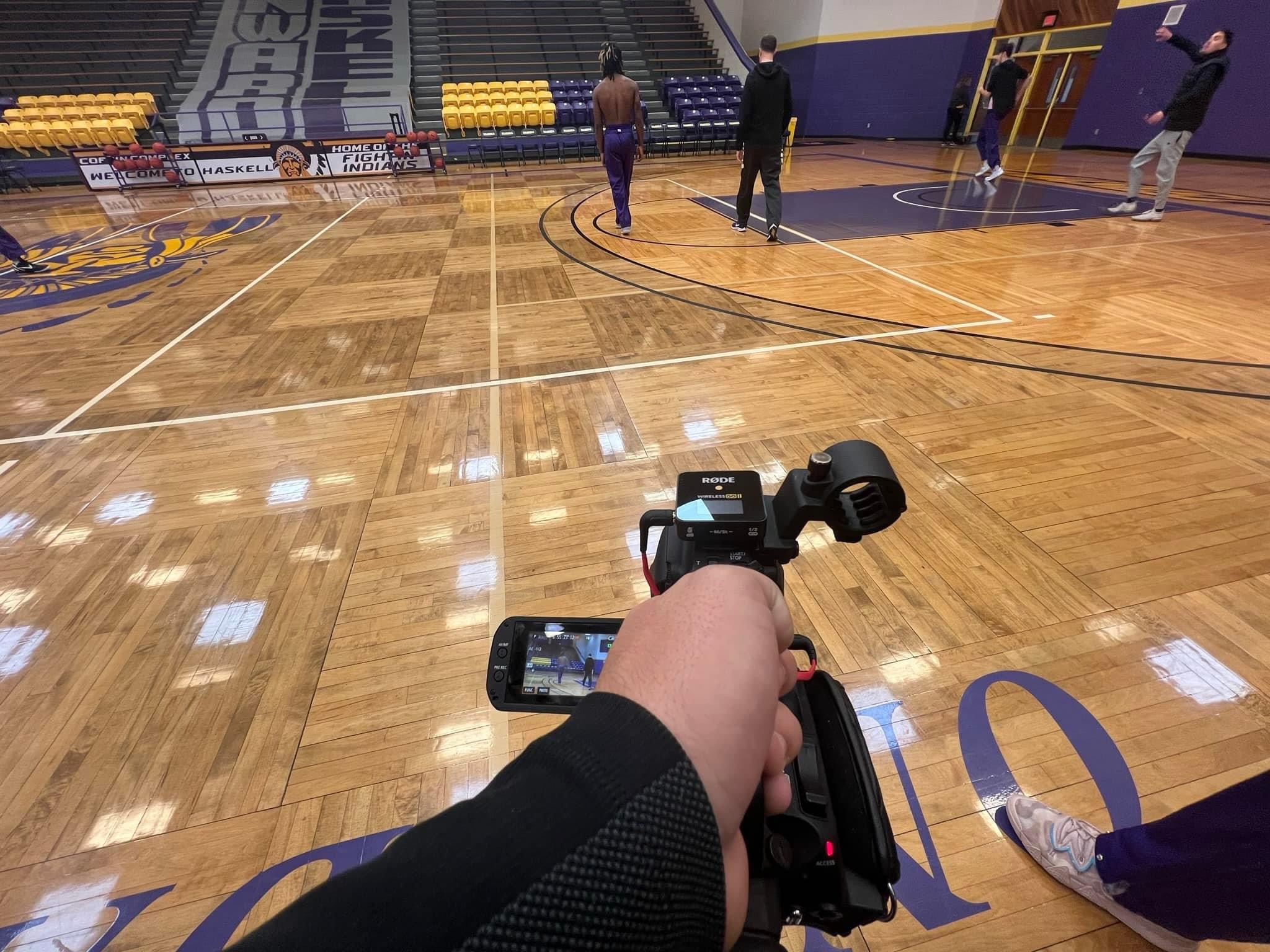 student holding camera in basketball gym