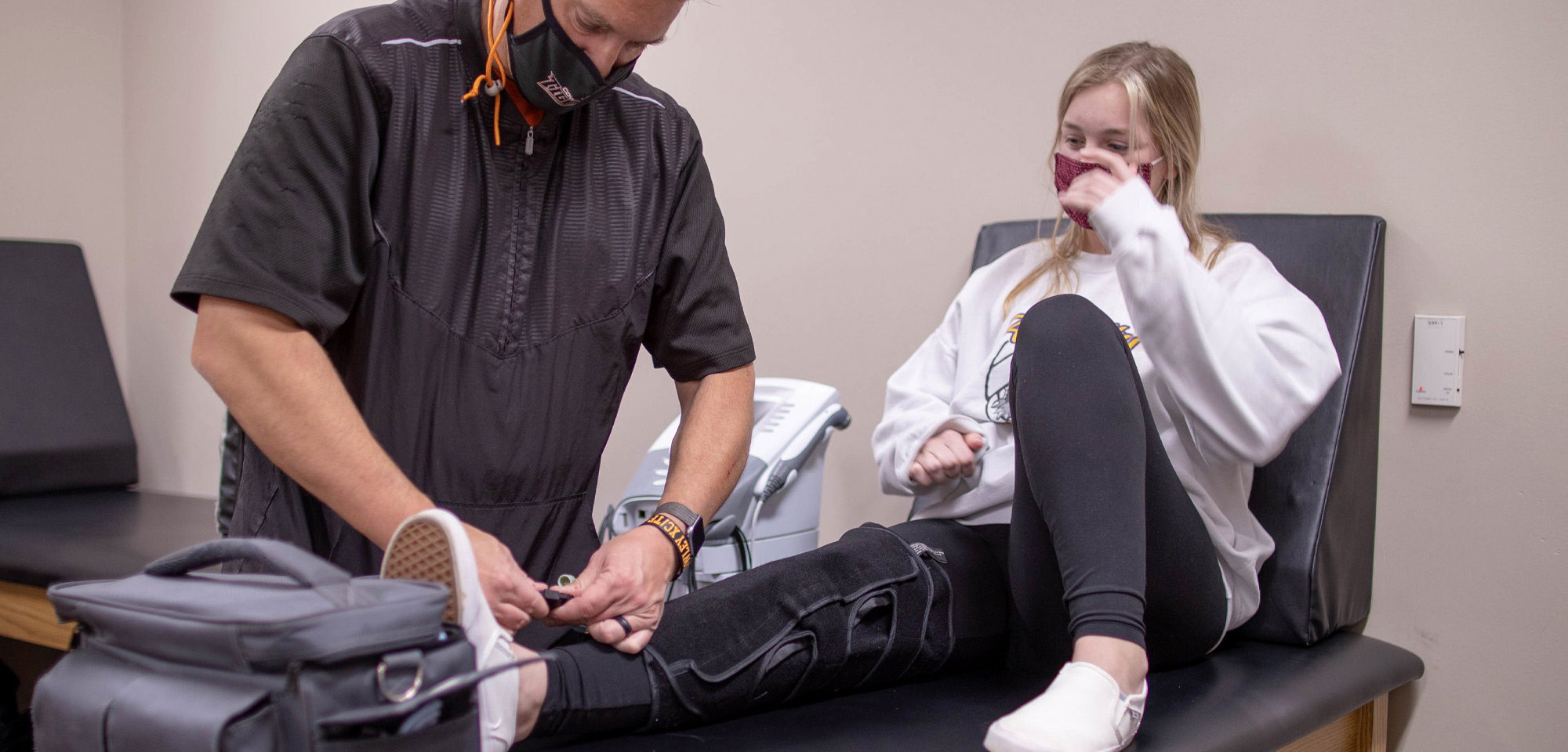 athletic trainer putting a brace on an athlete