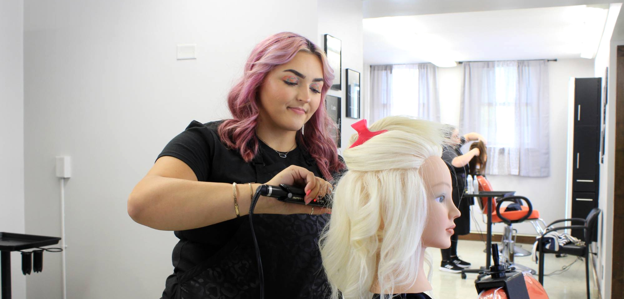 student curling hair on a mannequin